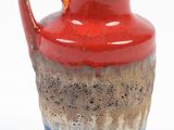 a red and blue vase with a handle on a white background