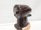 un objet marron posé sur un socle, sur une surface blanche