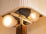 lamps on a wooden pole with a beige shade on top of it
