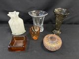 Plusieurs vases en verre de formes variées sont posés sur une surface noire