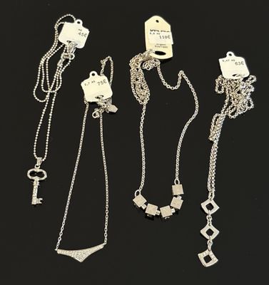four different types of silver necklaces and a key on a black background