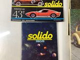 three books on a table with a car and a car in the background