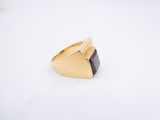 a gold and black stone ring on a white surface