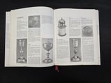 an open book with a bunch of silver items on it