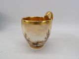 a gold cup with a handle on a white table