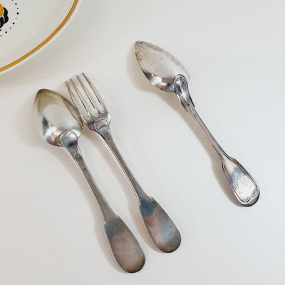 two silver spoons and a fork on a white table