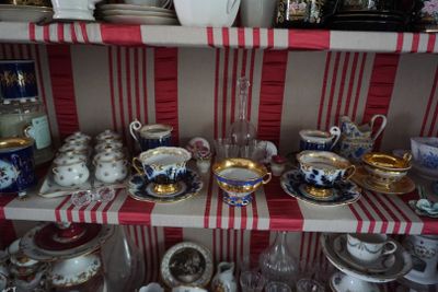 de nombreuses tasses et soucoupes posées sur une étagère dans une pièce