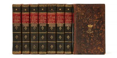 six vieux livres sont alignés sur une surface blanche