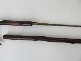two old wooden canes on a white surface
