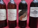 four bottles of wine are lined up on a pink background