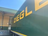a green and yellow train that is parked in front of a building