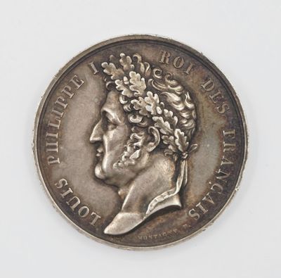 une vieille pièce d'argent sur laquelle figure le portrait d'un homme coiffé d'une couronne de fleurs