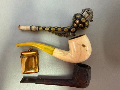 a pipe, a cigarette holder, and a lighter on a table