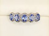 a close up of a blue and white diamond ring on a white surface