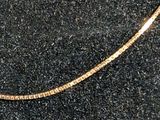 an image of a gold necklace on a black surface