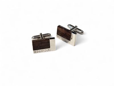 une paire de boutons de manchette en bois sur lesquels sont gravées des initiales