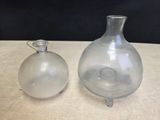 two glass vases sitting on a table next to each other