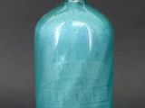 blue glass soap dispenser with a metal handle on a black background