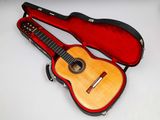 une guitare dans un étui, posée sur une surface blanche