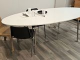 une table blanche avec quatre chaises et un ordinateur portable posé dessus