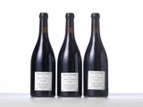 three bottles of wine are lined up on a table