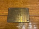 a metal plaque on a wooden table that has a monogram on it