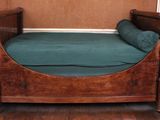 a wooden bed with a green cover on it in a room
