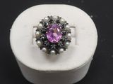 une image représentant une bague ornée d'une pierre rose entourée de perles