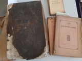 de nombreux livres anciens posés sur une table, recouverts de papiers