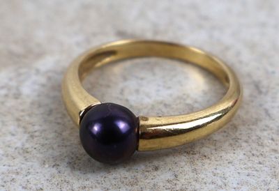 un gros plan d'une bague ornée d'une perle violette