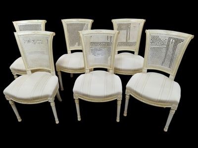 Six chaises à dossier renversé canné en bois laqué crème.