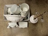 beaucoup d'assiettes et de tasses blanches dans une boîte posée par terre