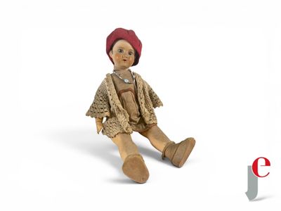 a small doll sitting on the ground with a red hat