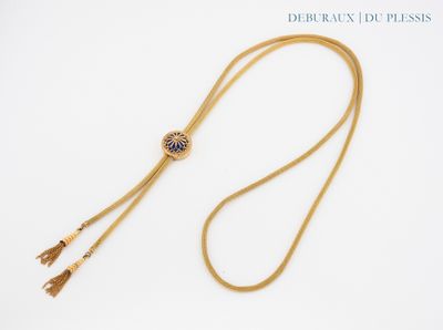 a close up of a gold necklace with a tassel on a white background