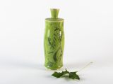 un vase vert orné d'une feuille sur le côté