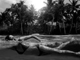 photographie en noir et blanc d'une femme en bikini allongée sur une planche de surf
