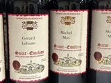 six bottles of red wine are lined up on a table