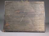 an old wooden box with a handle on a gray surface
