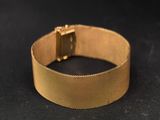 a close up of a gold bracelet on a black surface