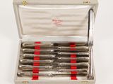 four silver and red pens in a silver case on a white surface