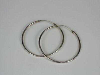 two silver hoop earrings on a white surface
