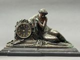 a statue of a woman with a clock on a table