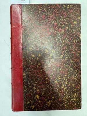 un vieux livre à la couverture rouge posé sur une table blanche