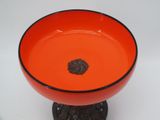 an orange bowl with a black rim sitting on a table
