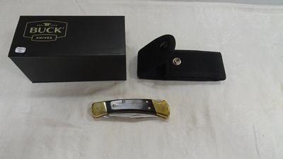 une boîte noire et un couteau de poche doré posés sur une table blanche