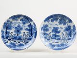 pair of blue and white plates with figures and trees on them