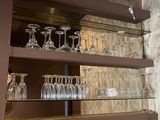 a glass shelf with wine glasses on it in a room