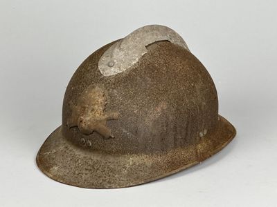 un vieux casque qui a été porté par un homme et sur lequel se trouve un chapeau