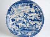 assiette bleue et blanche représentant un homme dans un bateau sur l'eau
