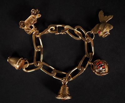 un gros plan d'un bracelet en or orné de breloques sur fond noir